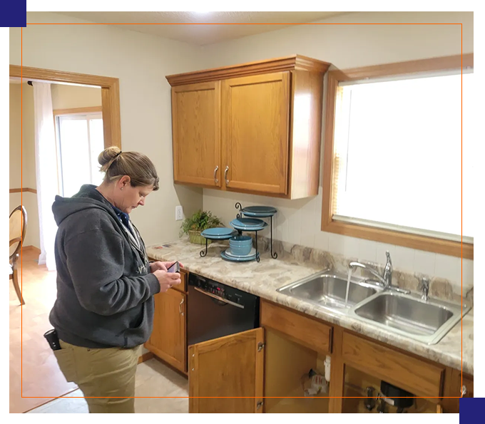 A woman standing in the kitchen looking at her phone.